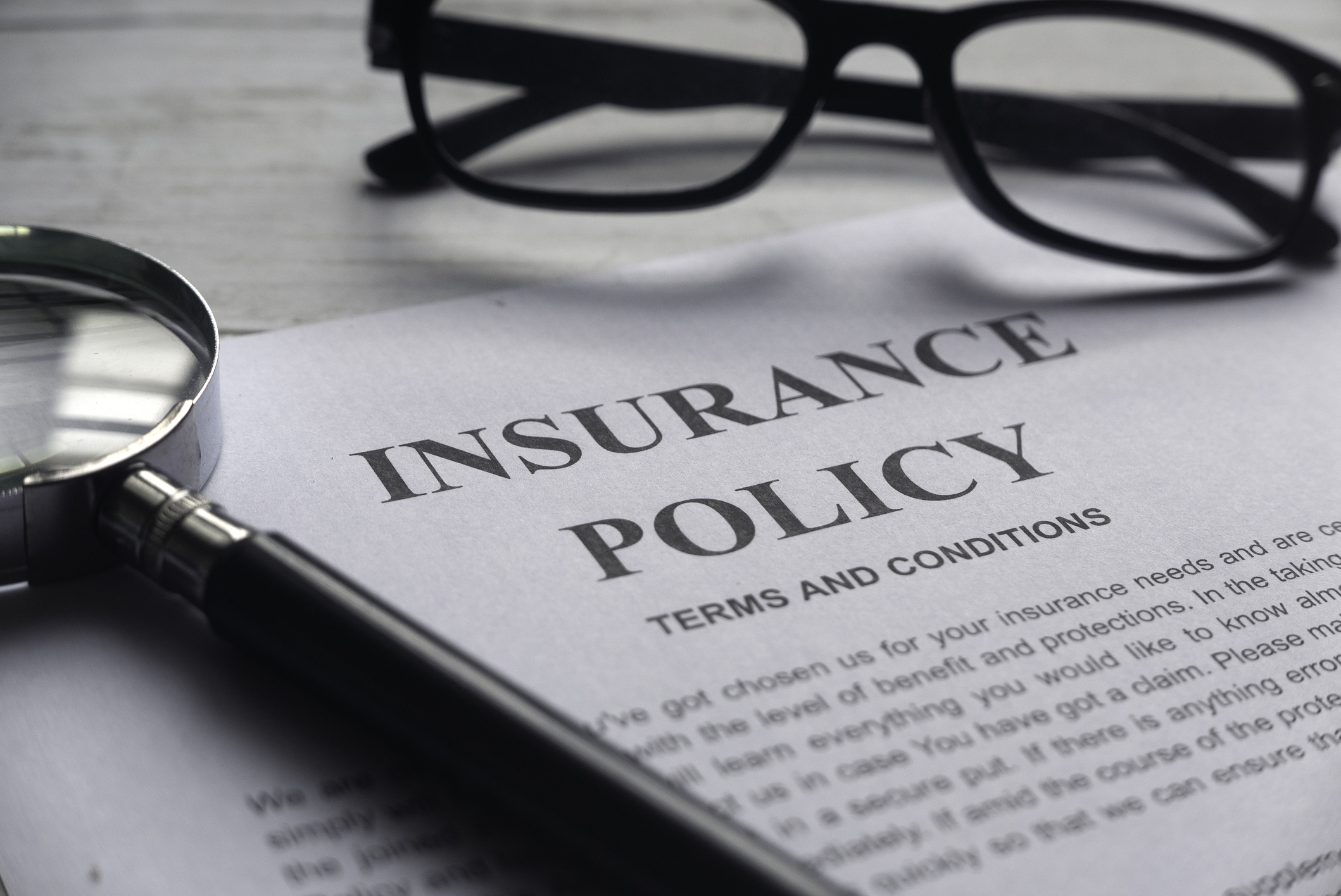 a reading glass and insurance policy documents