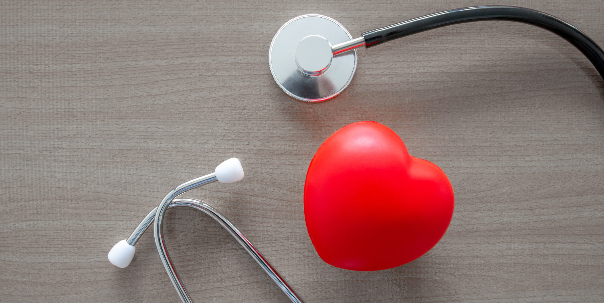 stethoscope and glow red heart on wooden table.